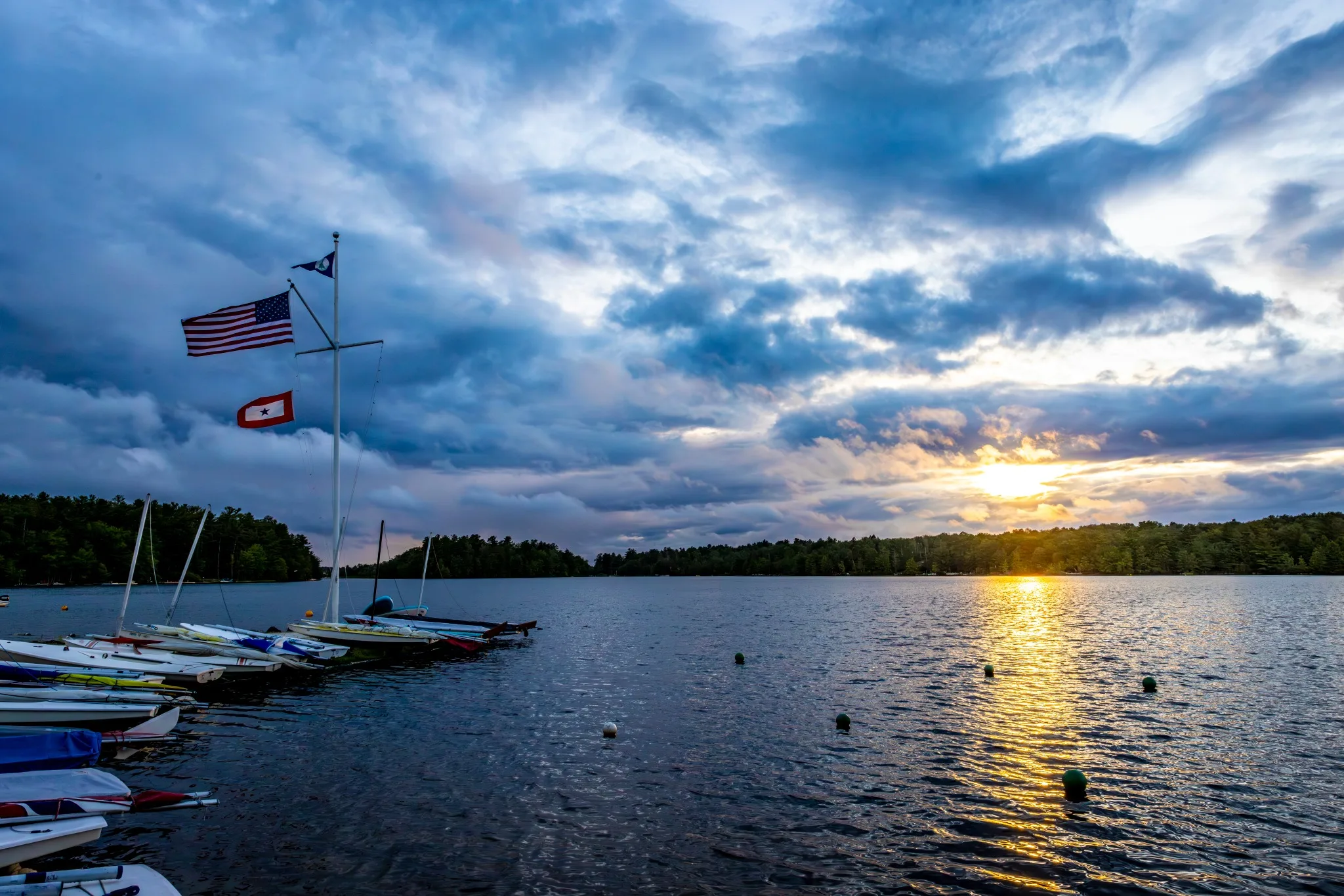 Lake Naomi sunset with boats, flag, and dramatic clouds