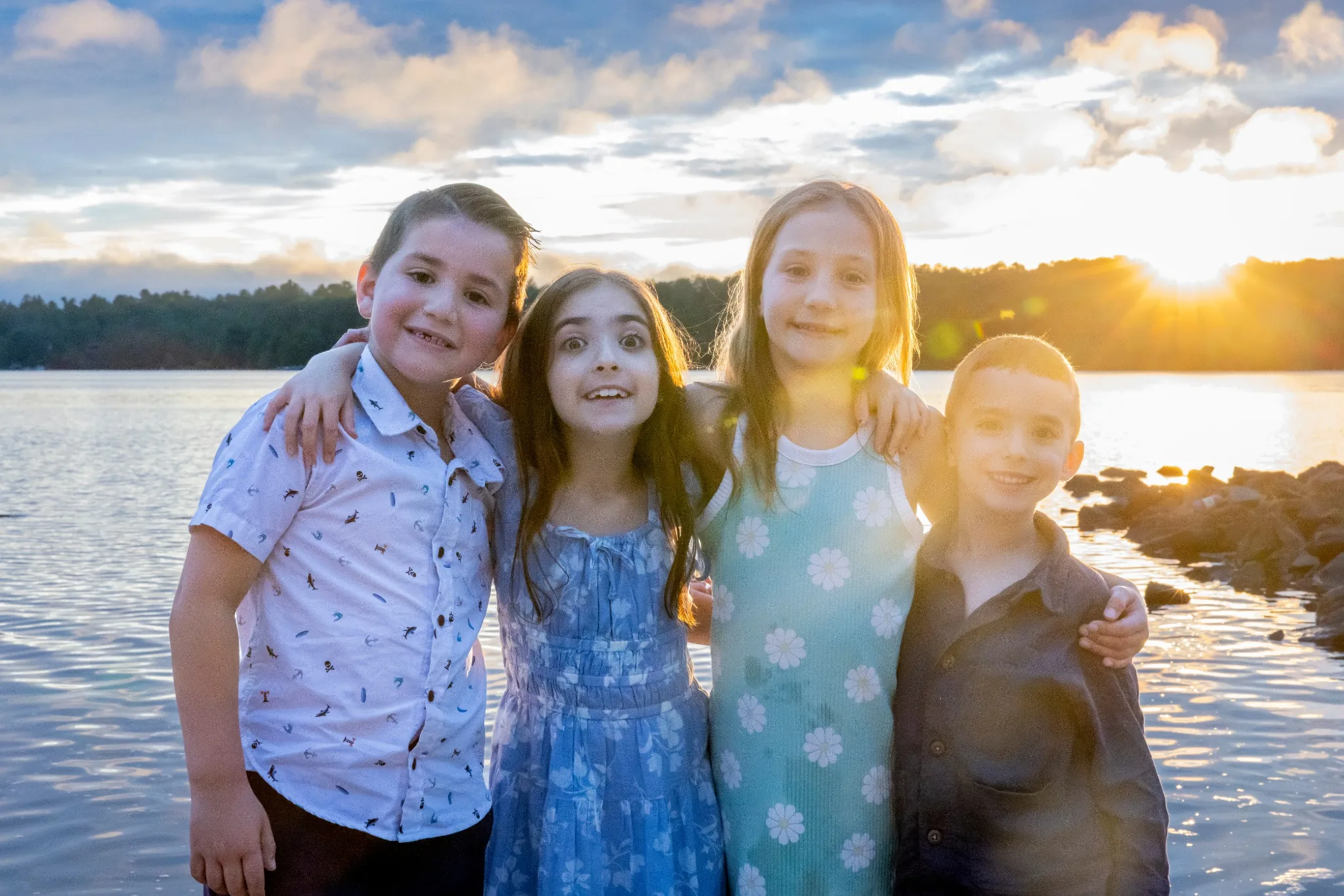 Four children posing together beside Lake Naomi at sunset